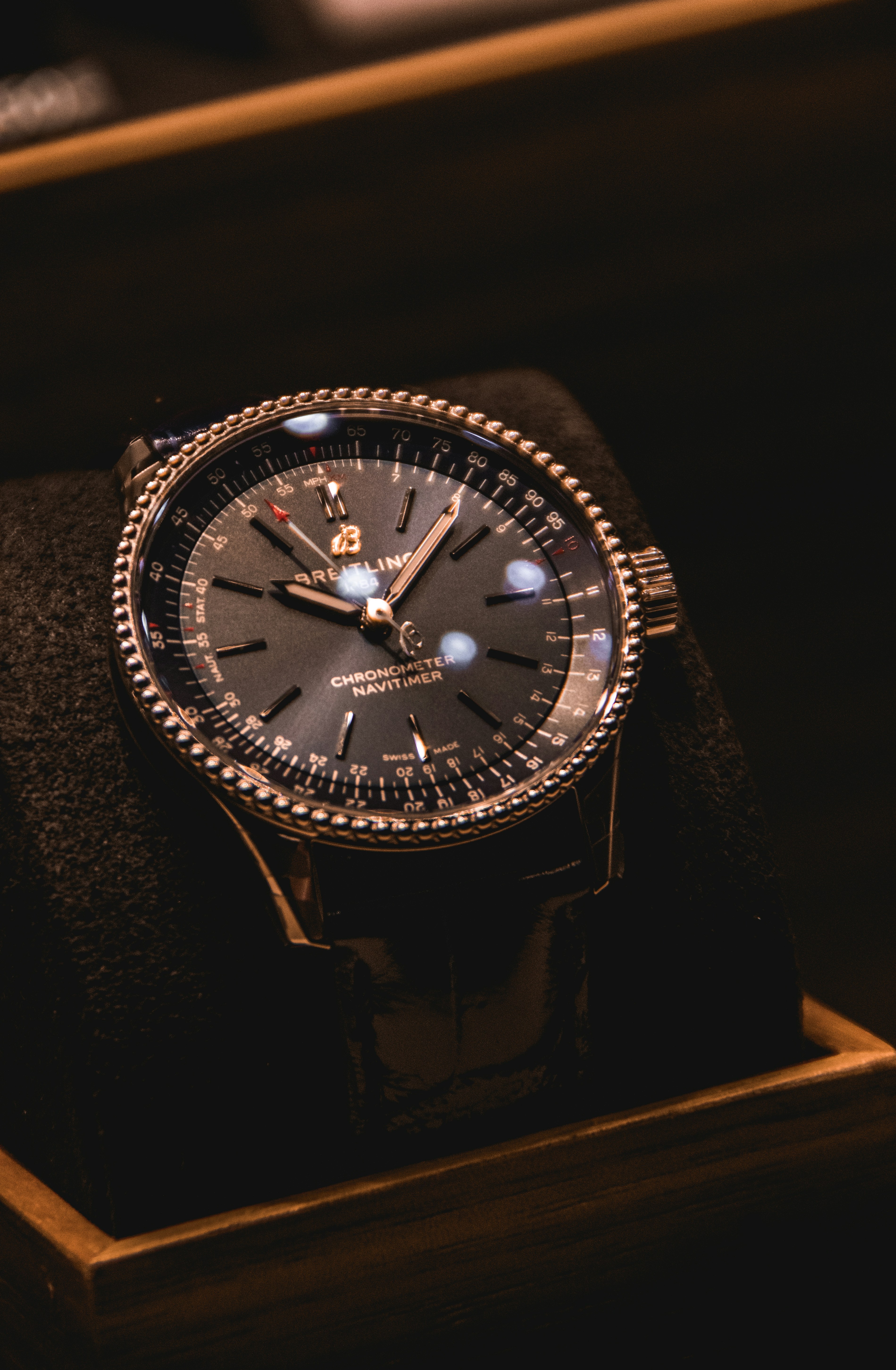 Breitling chronograph on a dark surface, case and bezel in editorial studio lighting